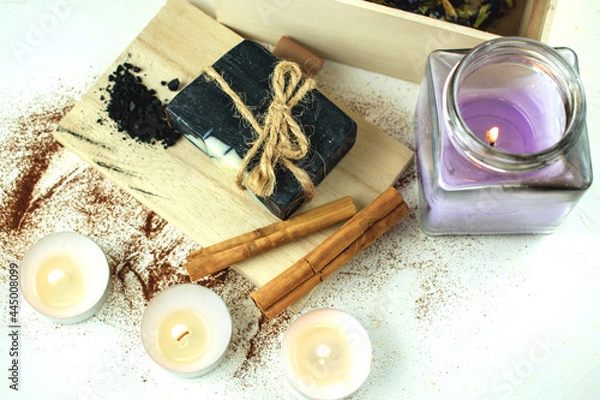 Obraz Block of natural carbon soap on a wooden board, burning spa candles