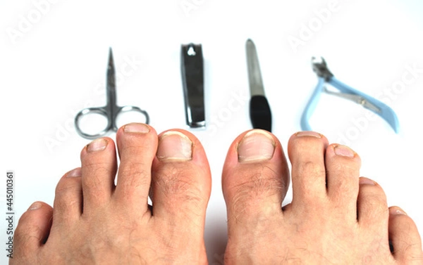 Obraz Two feet with nails on a white background with pedicure tools.