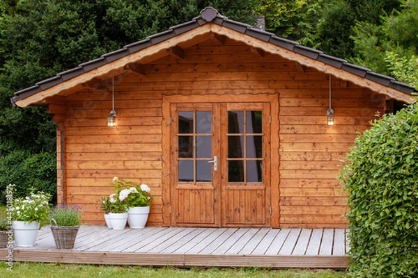Fototapeta  flowers in front of a wooden hut. Garden joy in summer. Relax in the garden and enjoy the beautiful weather. Lavender and hydrangea in pot next to a garden shed 