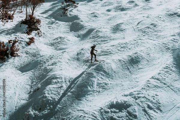 Fototapeta People in winter enjoying the snowy mountains where are practised plenty of activities such as skiing and snowboarding with a clear sky and some clouds on the horizon.