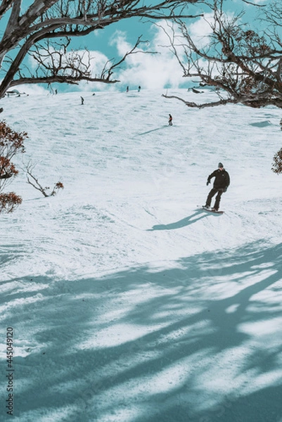 Fototapeta Ludzie w zimie cieszące się śnieżnymi górami, w których ćwiczą wiele zajęć, takich jak narciarstwo i snowboard z czystym niebem i chmurami na horyzoncie.