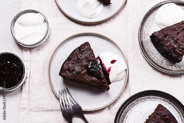 Fototapeta Slices of rich moist chocolate cherry cake. Homemade dark chocolate sweet brownies cakes with ice cream on greige linen tablecloth. Selective focus