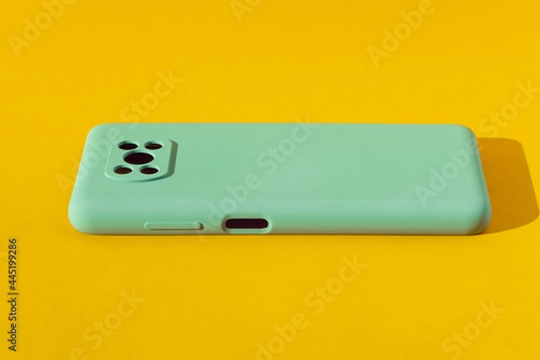 Fototapeta Light green silicone case for a smartphone on a yellow background, copy space.