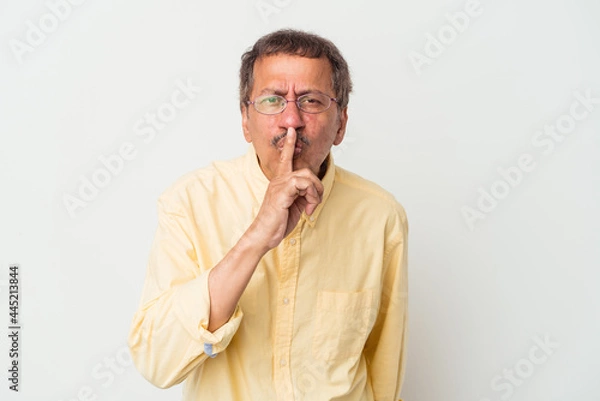 Fototapeta Middle aged indian man isolated on white background keeping a secret or asking for silence.