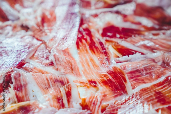 Fototapeta Appetizing slices Iberian ham in the foreground. Plate of Iberian ham Acorn-fed Iberico Ham. Pata negra, spectacular vision of sliced ham. Typical spanish or catalan food. Close up view.