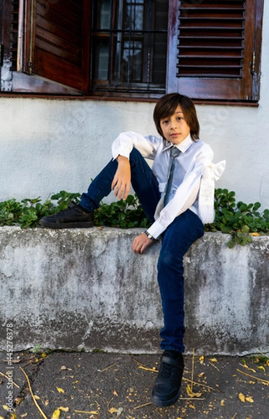 Obraz child dressed for holy communion seated under a window