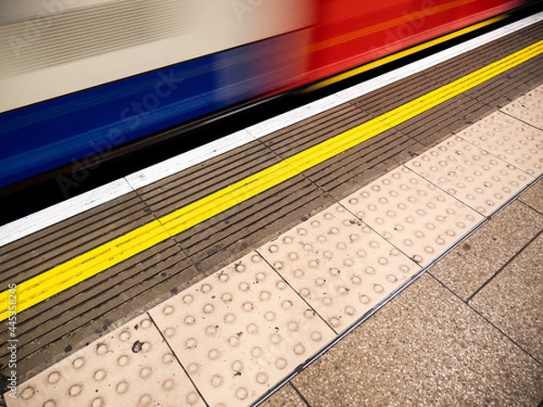 Fototapeta London Underground. A Central Line tube train passing the platform at speed to create an abstract background motion blur.