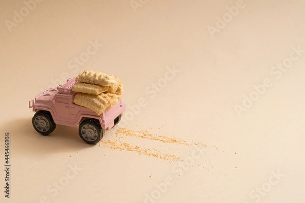 Obraz Cute pale pink toy truck delivering biscuits on a pink background with copyspace minimal