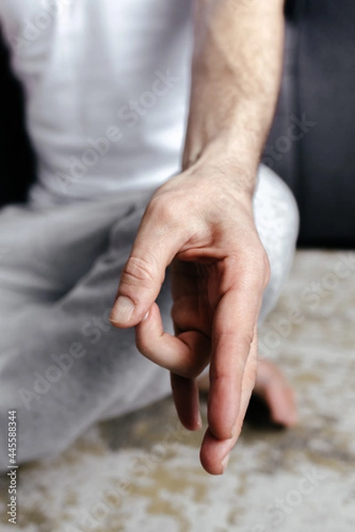Fototapeta A brutal man sitting in meditation with his hands folded in yoga mudras