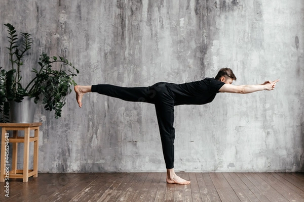 Fototapeta A young man performing yoga asanas and sports exercises to improve the strength and flexibility of the body