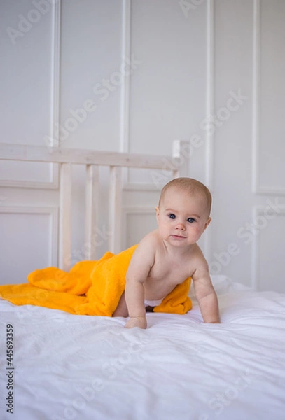 Fototapeta a baby girl in a diaper and with an orange towel crawls on the bed. Child development