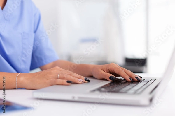 Fototapeta Close up of medical specialist typing on laptop in hospital office. Health practitioner searching in hospital database using laptop in hospital cabinet, keyboard, job.
