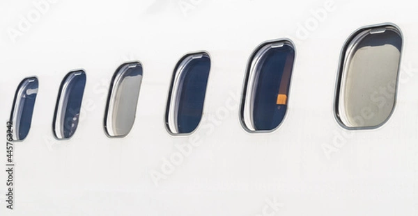 Fototapeta Fuselage of a white aircraft with windows, seen from outside.