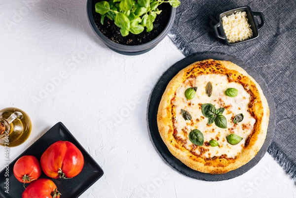 Fototapeta Traditional Margherita Pizza with basil, tomato, olive oil, mozzarella on a rustic background