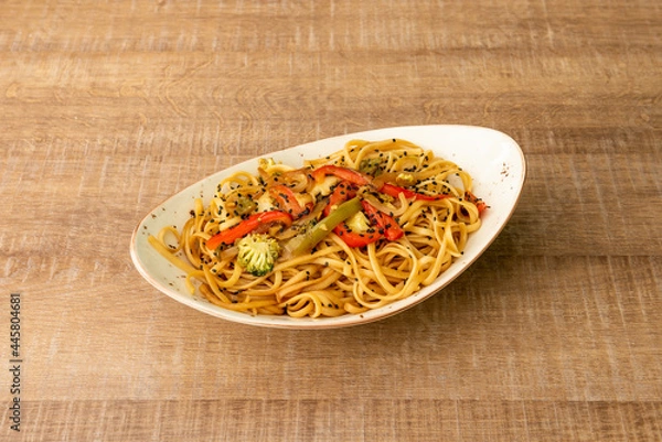 Fototapeta Chunky noodles sauteed with vegetables and broccoli with lots of soy sauce and poppy seeds cooked by a Chinese chef