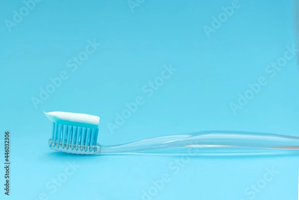Fototapeta Blue toothbrush with paste on a blue background. Close up. Space fot text.