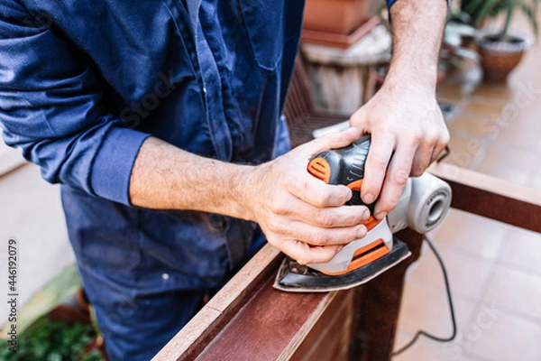 Fototapeta white caucasian man sanding wooden table, selective focus