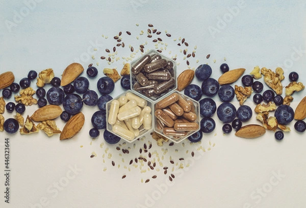 Fototapeta Various capsules with dietary supplements or vitamines, fresh blueberry and nuts