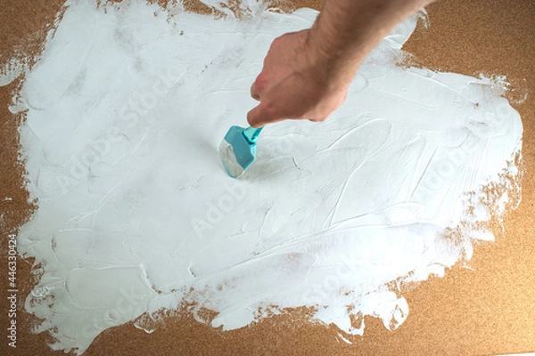 Obraz A man applies white plaster with a spatula