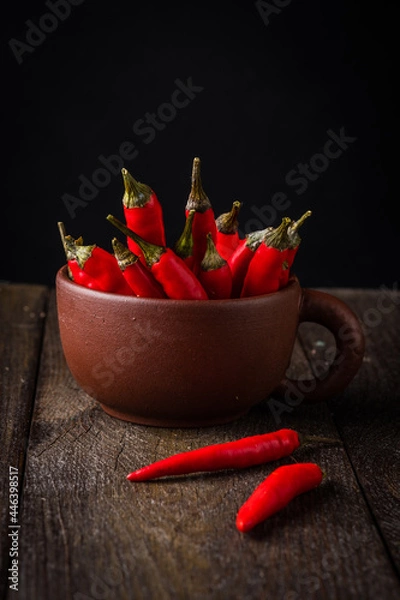 Fototapeta Red chili peppers in a clay chashketna dark background.