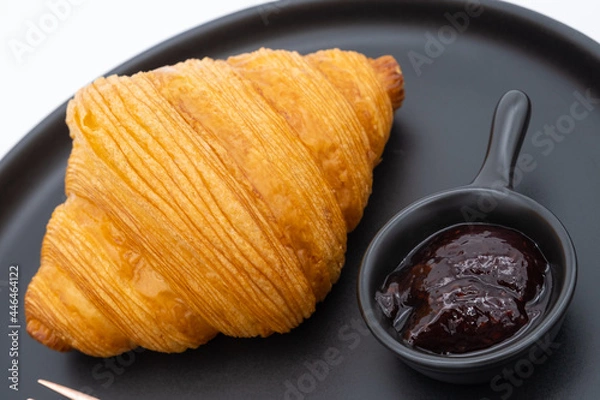 Fototapeta Croissant with mixed berry jam on black plate isolated on white background.