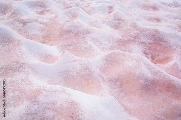 Fototapeta White and pink melted snow interspersed with red lies bumps