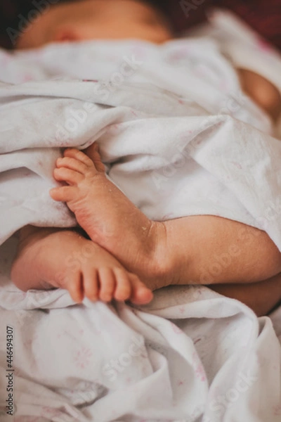 Fototapeta Low section of baby wrapped in sheet lying on bed.