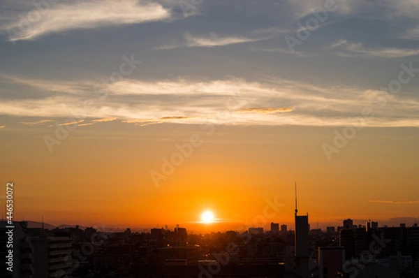 Fototapeta 兵庫県神戸市東灘区のマンション高層階から撮影した日の出。梅雨明け後、まだ雲が残るが、オレンジ色に染まりドラマチックな都会の朝。