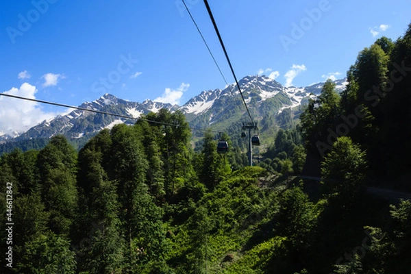 Fototapeta ropeway cabins in caucasus mountains covered with forest and snow
