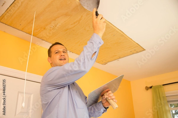 Obraz Handyman in uniform spackling ceiling