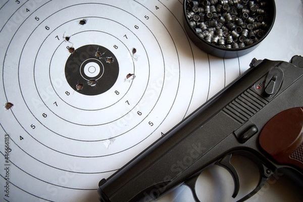 Fototapeta A sports pistol on the background of a target with bullet holes and lead bullets.