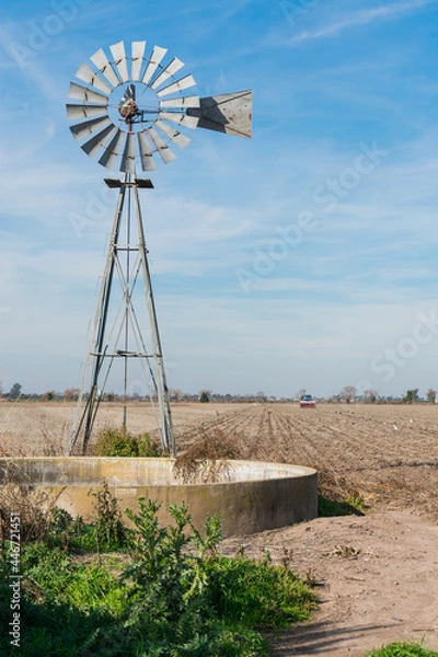 Fototapeta Old water mill in the middle of a field while it is being planted. Pool to give water to the animals