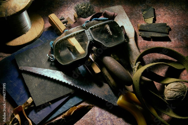 Obraz The table is littered with a bunch of old things, construction tools, objects in the workshop. Safety glasses. Close-up.
