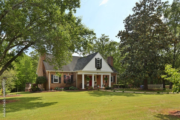 Fototapeta Family house surrounded by trees and well-maintained yard