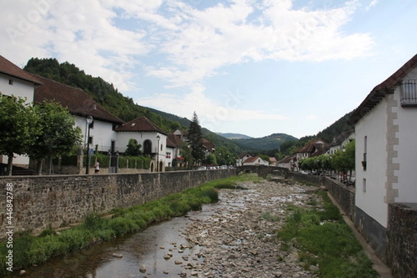 Fototapeta River with little water and stones, vegetation and a bottom bridge, with bottom houses in Otsagabia, Navarra