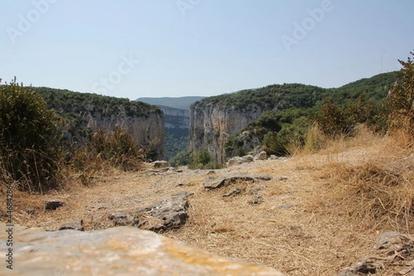 Fototapeta Cliffs with a lot of vegetation and in the foreground some rocks in the Foz de Arbaiun in Navarra, Spain