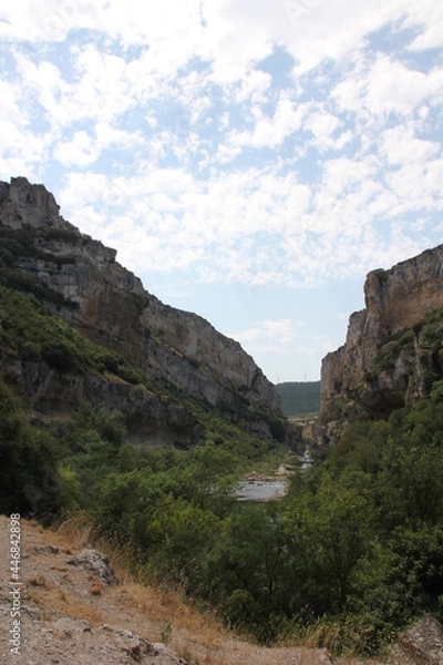 Fototapeta Cliffs of large rocks with vegetation and two windmills in the background at the Foz de Lumbier in Navarra