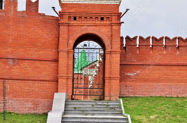 Obraz A high red brick fence with carved gates and stairs to the gate. High quality photo