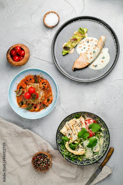 Fototapeta table full of seafood. salmon steak grilled shrimp and squid salad with avocado top view, seafood table concept