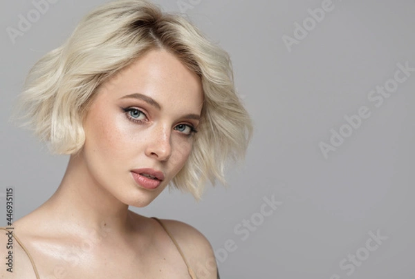 Obraz Portret pięknej blondynki z krótką fryzurą. Szare tło.