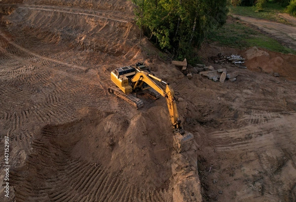 Fototapeta Excavator dig ground at construction site. Foundation pit for a multi-story building. Earth-moving heavy equipment. Arial view of the Digger on earthworks. Trench for laying external sewer pipes.