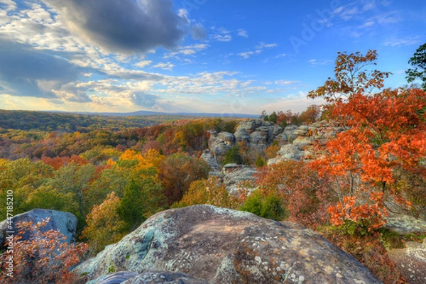 Fototapeta unusual rock formations on the top of a mountain surounded by an Autumn colored forest fading to a distant horizon under a painted sky, Garden of the Gods Illinois