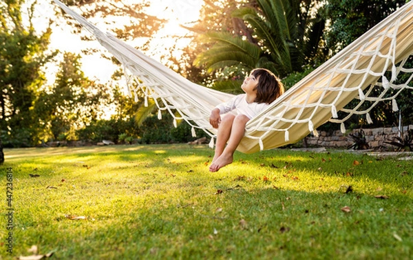 Fototapeta Cute little barefoot toddler boy relaxing in hammock in backyard garden looking at sky. Child summer holidays healthy lifestyle and outdoors leisure activity. Vacation at home