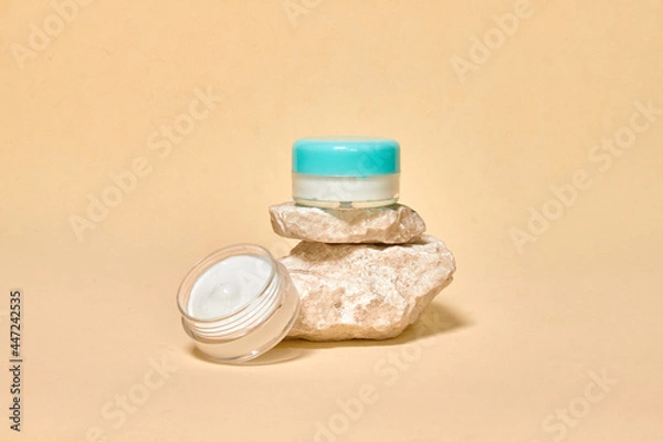 Fototapeta Cosmetics container on the pastel background. Natural stones. Earth colors, zero waste containers. Mockup concept. Copy space for text or design. Can be used as advert banner.