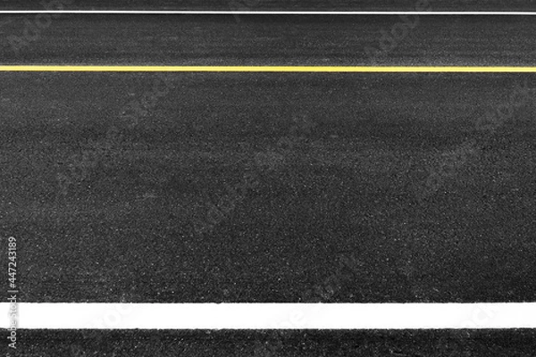 Fototapeta Close up black asphalt road surface texture with a separation yellow and white line.