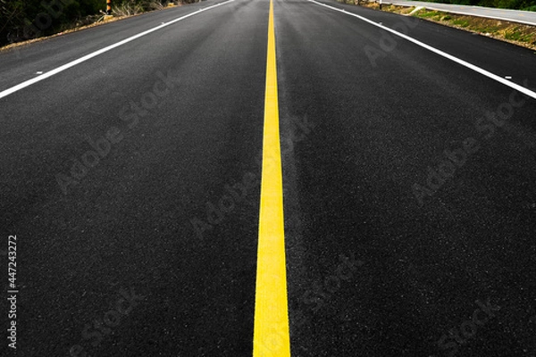Fototapeta Close up of local black asphalt road surface texture with a separation yellow line. Selective focus.