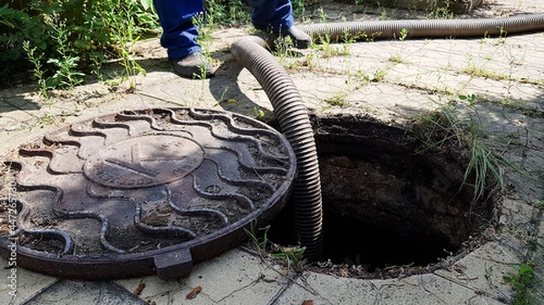 Obraz the worker opened the sewer hatch and inserted a hose for cleaning the septic tank. maintenance of communications in a private house
