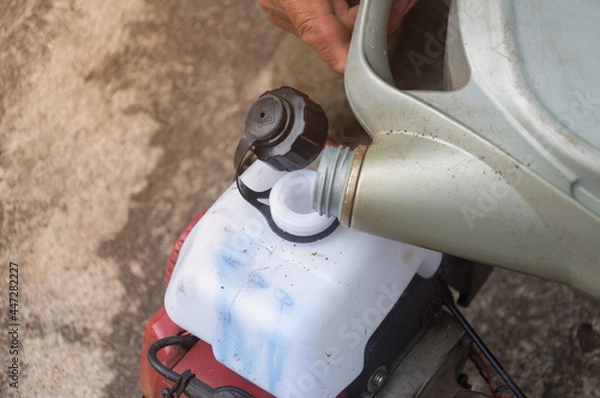Fototapeta man's hand holds a tank of fuel and pours it into the engine.