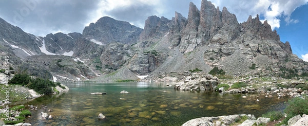Fototapeta Panoramic view of sky pond in Rocky Mountain National Park in Colorado. Sharp teeth-like peaks can be seen as well as the blue-green water of the pond and patches of snow.