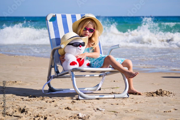 Fototapeta Ребенок сидит на шезлонге с игрушкой